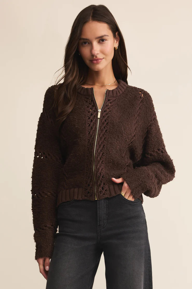 Woman wearing a brown knitted cardigan with a zipper on a beige background