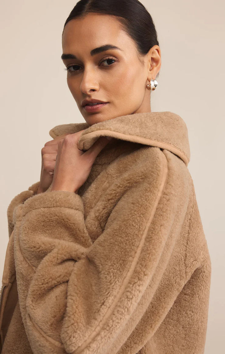 Woman wearing a beige robe against a plain background