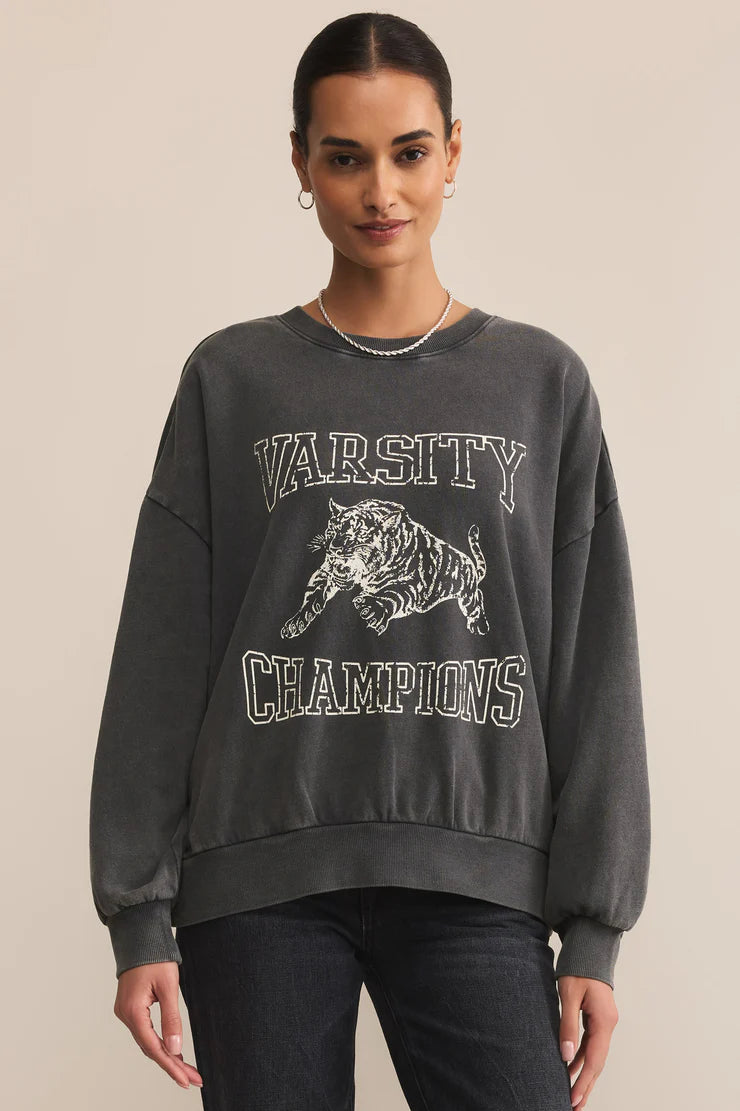 Woman wearing a dark gray sweatshirt with 'Varsity Champions' text and tiger graphic on a beige background