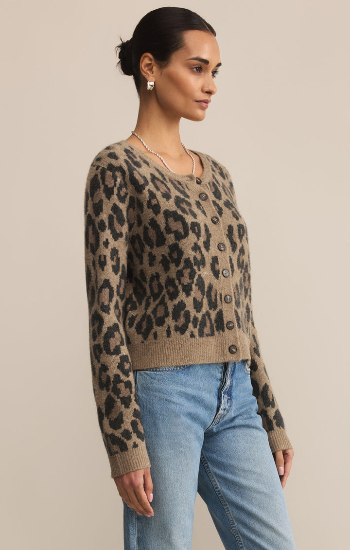 Woman wearing a leopard print sweater and blue jeans against a beige background