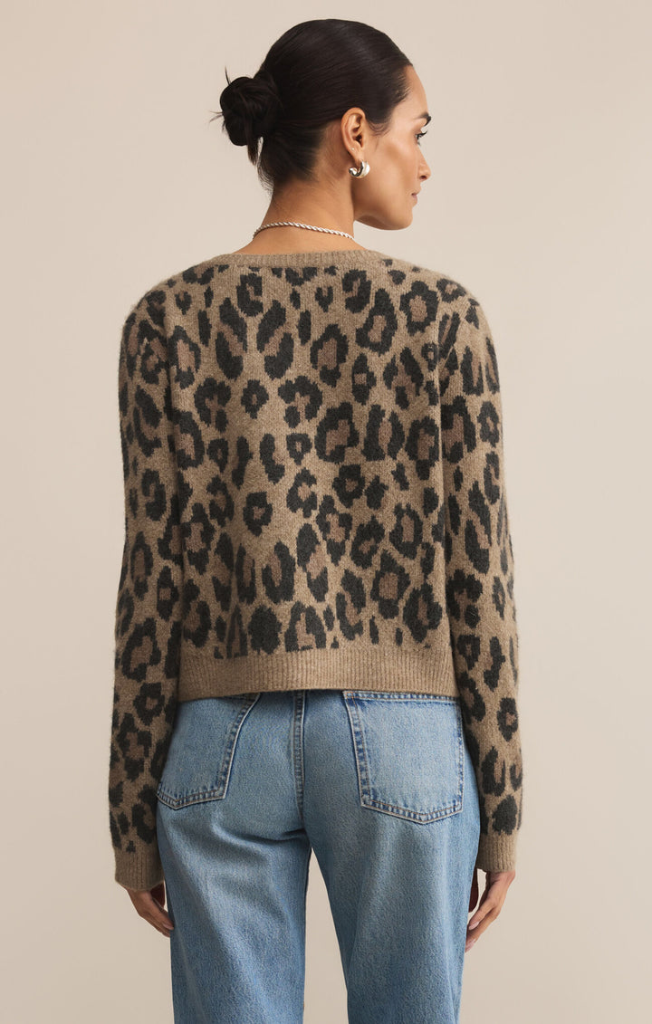 Person wearing a leopard print sweater and blue jeans on a beige background