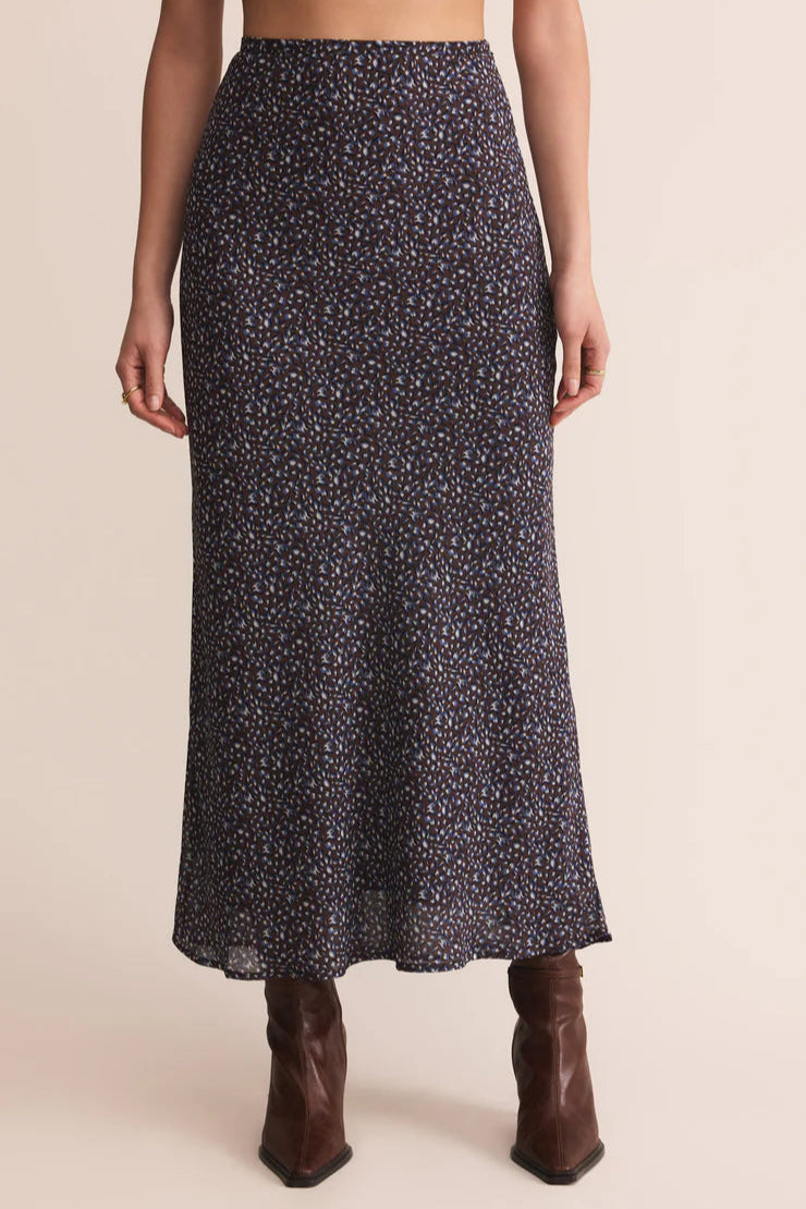 Person wearing a patterned skirt and brown boots on a beige background