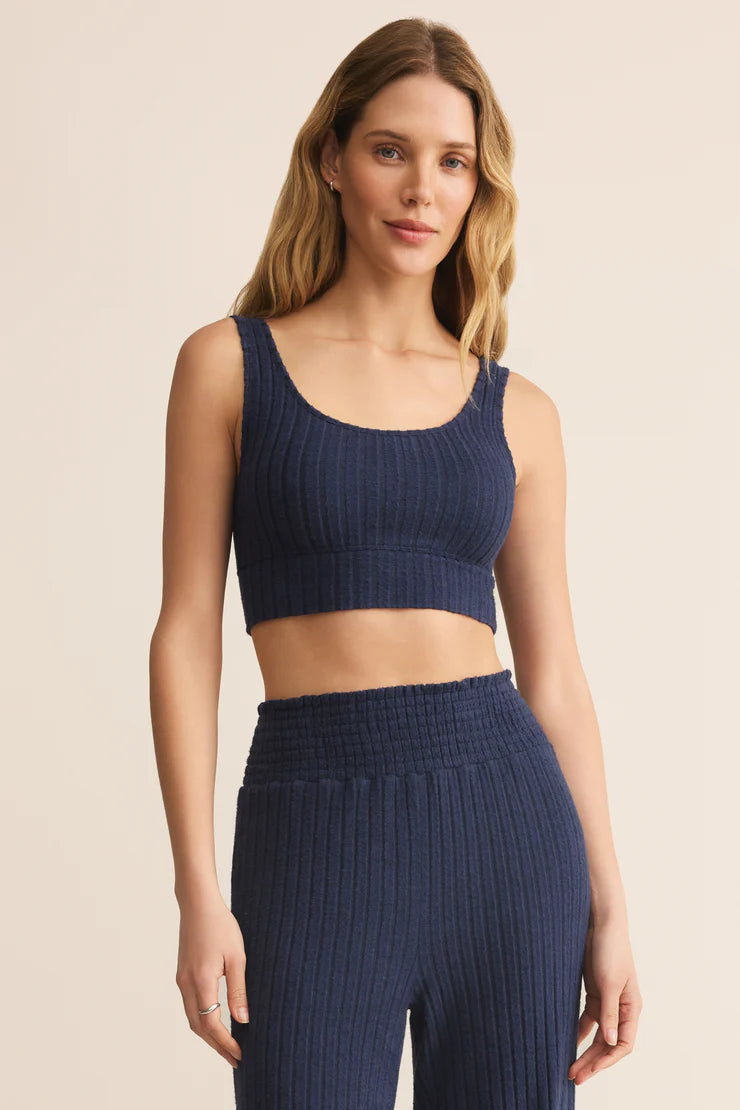 Woman wearing a navy ribbed tank top and leggings on a beige background