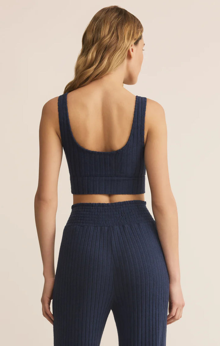 Person wearing a navy ribbed knit outfit on a beige background