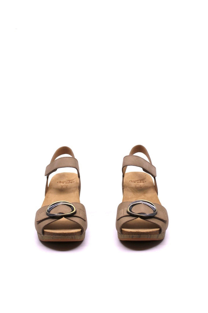 wedge ankle strap sandal with leather straps buckle closures and a cork wedge in light tan color by dansko