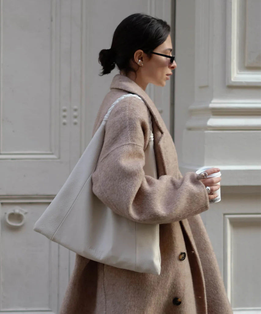 Crafted from real leather suede and featuring warm-toned neutrals, this bag is perfect for upgrading chunky sweaters or flowy maxis. The signature braided handle adds a touch of sophistication.